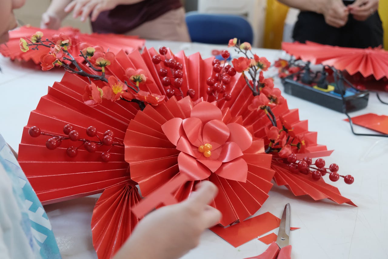 Services Close-up of hands creating red paper crafts with flowers and berries.